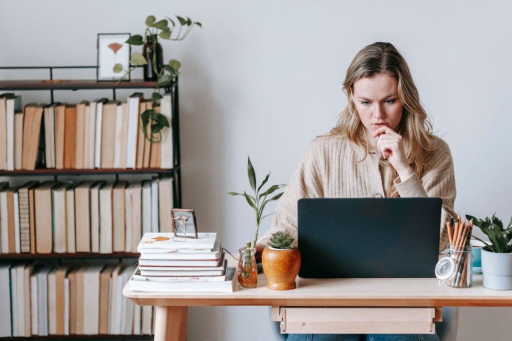 woman-browsing-laptop-near-books