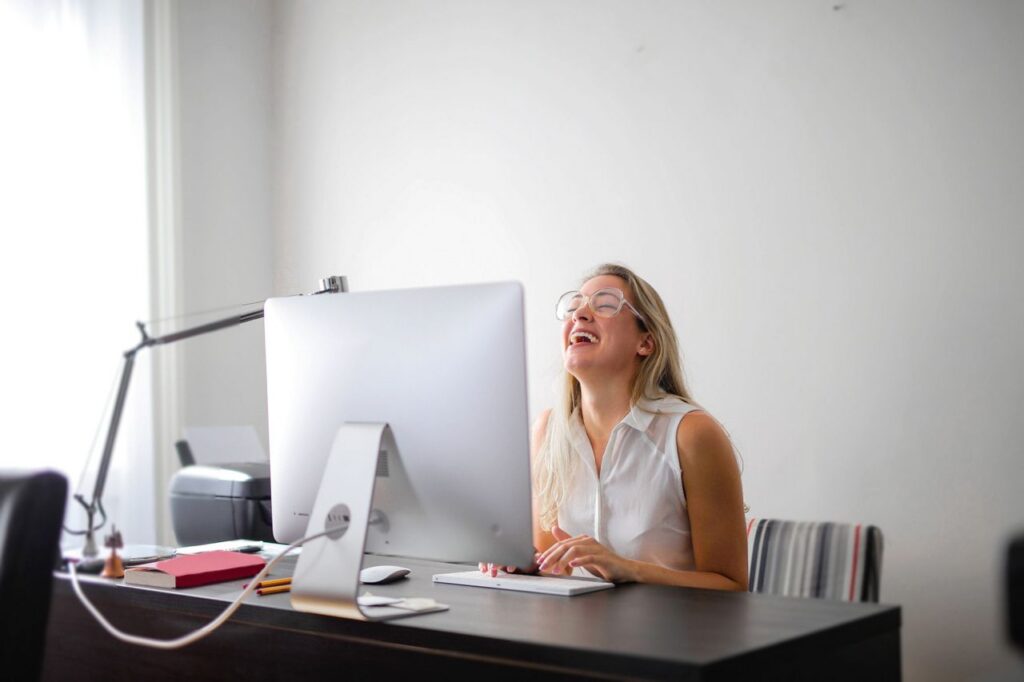 woman-in-white-tank-top-using-macbook-air-on-brown-wooden-table